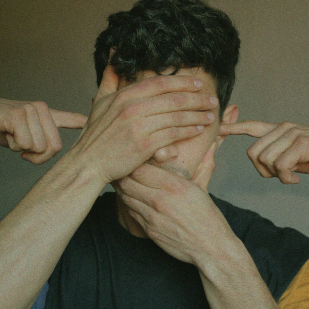 Conceptual image depicting a man with hands blocking his senses, symbolizing silence and perception blockage.